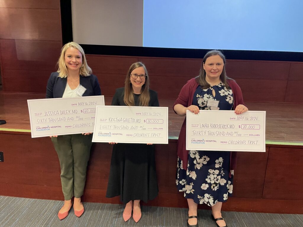 The three grantmakers finalists, standing side-by-side, each holding their own check for awarded funds.