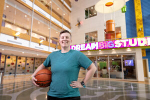 Recreation Therapy specialist, Tayler Tadrick, holding a basketball and smiling in the Atrium at UPMC Children's